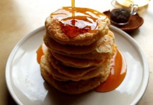 Delicious pancakes stacked high, drenched in syrup, perfect for breakfast lovers.