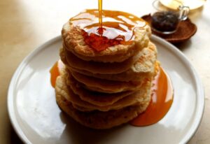 Delicious pancakes stacked high, drenched in syrup, perfect for breakfast lovers.